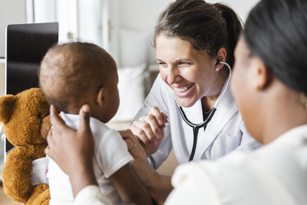 Provider Education Female pediatrician smiling at an infant patient.