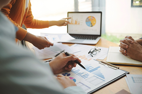 Reimbursement Landscape Assessment Medical device market access experts discussing reimbursement strategies at a desk with graphs and laptops.