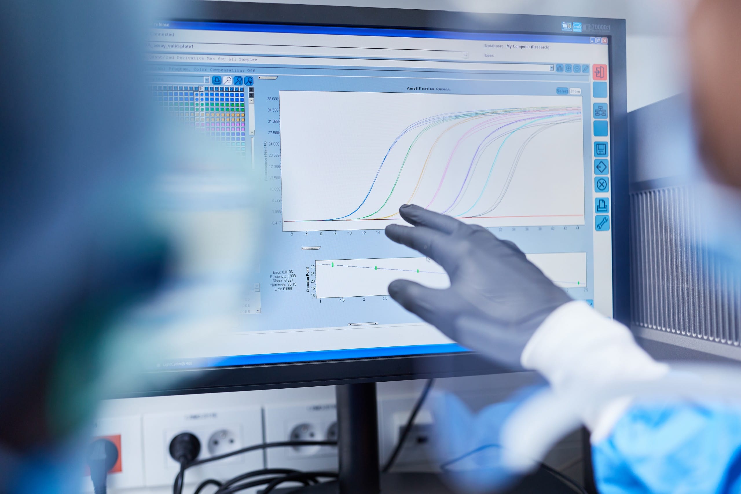 Data Analysis & Biostatistics Computer monitor showing various data and graphs, gloved hand of a scientist pointing at data chart.