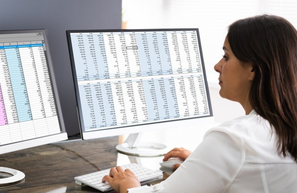 Due Diligence & Data Gathering Analyst conducting due diligence and studying data in front of two computer monitors.